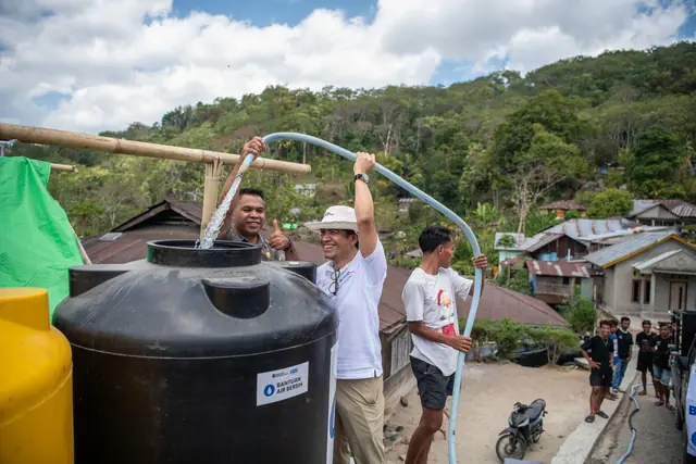 Villagers fit a bamboo pipe to a new water tank in a hillside NTT village