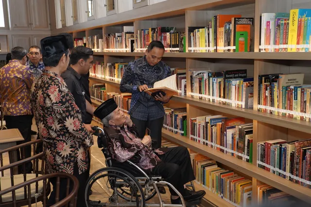 Library visitors including a wheelchair user browsing books on open shelves