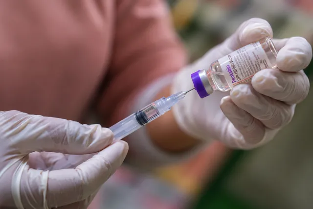 A health worker prepares a vaccine dose at a healthcare facility
